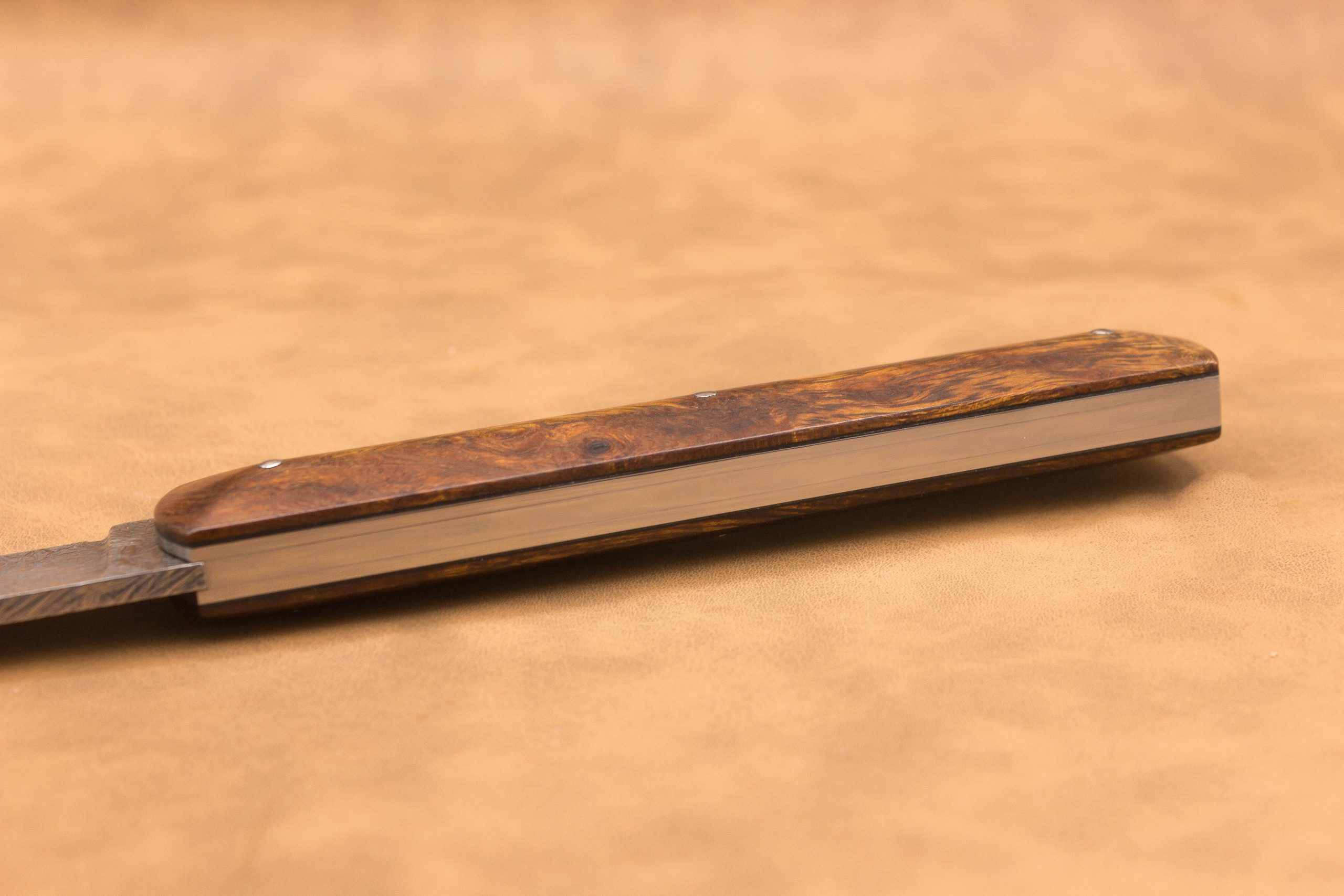 Vue générale : Couteau droit artisanal en damas mosaïque avec manche en bois de fer d'Arizona. Lame : Lame en damas carbone mosaïque forgée artisanalement. Manche : Manche en bois de fer d'Arizona sur couteau artisanal français. Dos : Dos poli d'un couteau à cran forcé fabriqué à la main. Étui : Étui en véritable cuir noir livré avec le couteau artisanal joel alexanian couteau d'art collection damas maison var