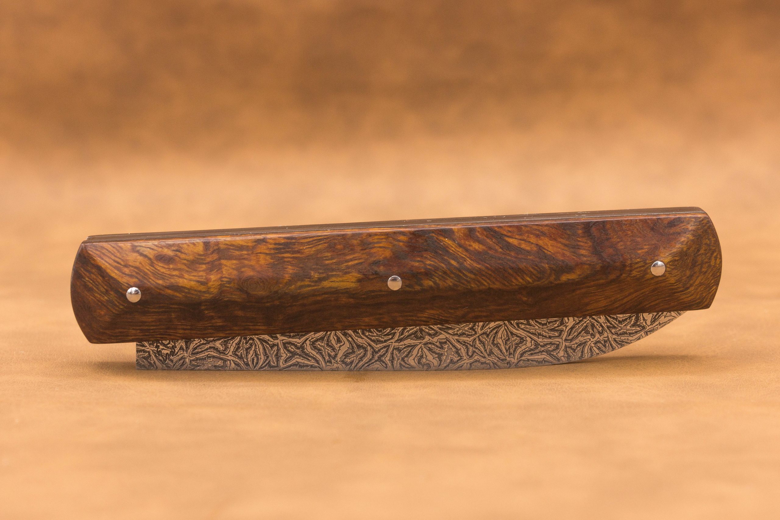 Vue générale : Couteau droit artisanal en damas mosaïque avec manche en bois de fer d'Arizona. Lame : Lame en damas carbone mosaïque forgée artisanalement. Manche : Manche en bois de fer d'Arizona sur couteau artisanal français. Dos : Dos poli d'un couteau à cran forcé fabriqué à la main. Étui : Étui en véritable cuir noir livré avec le couteau artisanal joel alexanian couteau d'art collection damas maison var