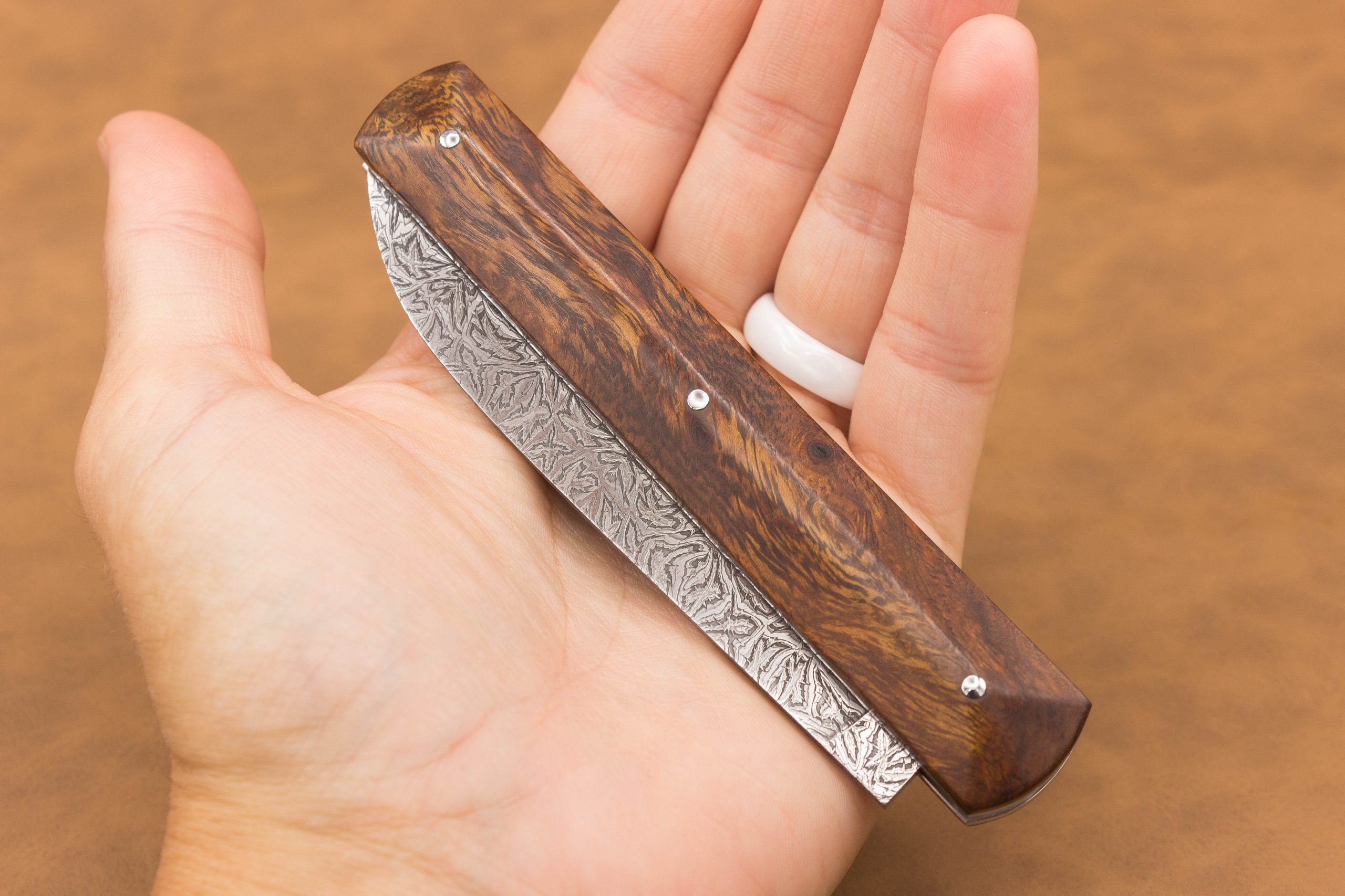 Vue générale : Couteau droit artisanal en damas mosaïque avec manche en bois de fer d'Arizona. Lame : Lame en damas carbone mosaïque forgée artisanalement. Manche : Manche en bois de fer d'Arizona sur couteau artisanal français. Dos : Dos poli d'un couteau à cran forcé fabriqué à la main. Étui : Étui en véritable cuir noir livré avec le couteau artisanal joel alexanian couteau d'art collection damas maison var